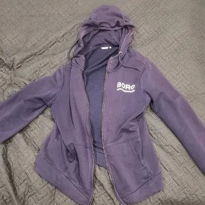 Björn Borg Hoodie - Detta är en Björn Borg hoodie som jag säljer. Den ser lite lila ut men den är mörk blå (måste blivit något färgfel i bilden) Denna hoodie har storleken "M". Har ej använts mycket bara några enstaka gånger. 