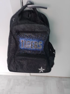 Ryggsäck  - Jättefin ryggsäck som min dotter har haft när hon höll på med Cheerleading i USA. Denna ryggsäck finns inte att köpa i Sverige. Det finns 4 fack och på sidan kan man ha sportflaska eller vattenflaska. Nypriset var 1000 kr.