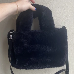 Fluffig svart väska, Monki  - Jättefin fluffig, mjuk väska från monki i liten storlek. Har ett axelband samt liten ficka inuti. Sparsamt använd, i fint skick. 