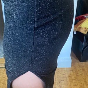 Svart glittrig klänning - Klänning från bikbok, har en tight passform med en slits på ena sidan och straps upptill. Passar perfekt till fest!