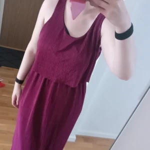 Jyothi klänning - 💥 Vinröd Jyothiklänning med lappar kvar säljes.  Resårband i midjan som gör att maxiklänningen ser tvådelad ut, silvrigt material inuti. Det är plisserad, ribbat och glansigt material. Väldigt bekväm och stretchigt material. 