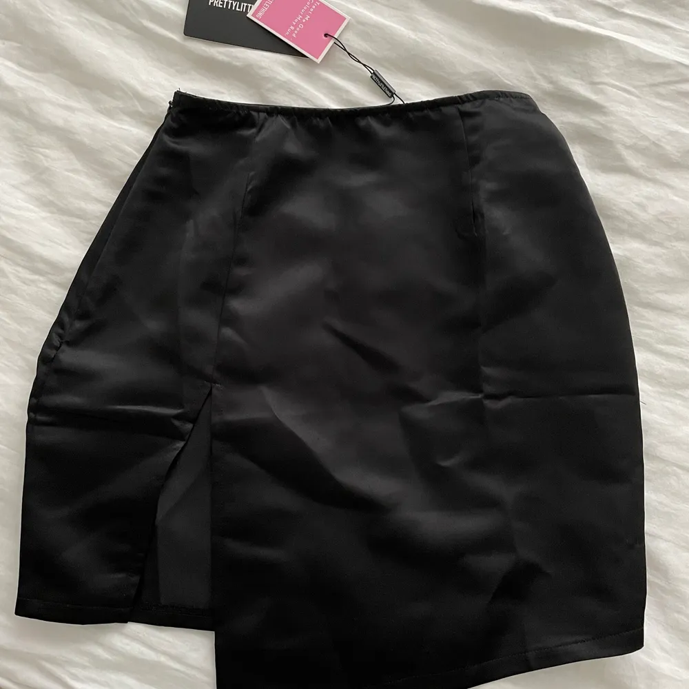 Svart satin aktig kjol med slits från Pretty little thing i strl 34🖤 Aldrig använd och prislappen kvar. Säljer för 100kr+frakt. Kjolar.