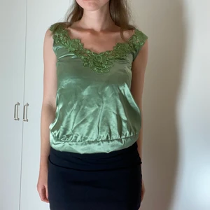 Festtröja i grönt  - Jättefin tröja i glansigt grön. Perfekt för fest. Fin färg. Storleken är Xs och märket är VILA. Inhandlad second hand. Fin kvalite bortsett från lagad slits i nedre hörnet. 