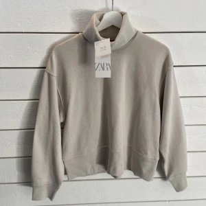 Tröja från Zara  - Helt ny! Aldrig använd. Ljusgrå/beige tröja från Zara. Sann till storleken. Går att justera kragen om man vill. Nypris 199:- Tillkommer frakt!