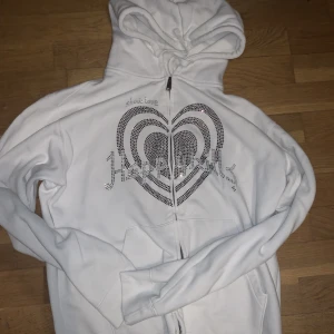 Rhinestone hoodie - Jag säljer min vita Happyhills Rhinestone ziptröja med bordersde lila pärlor. Använts sparsamt så den är i bra skick, 9/10. Skriv privat för mer info/bilder!