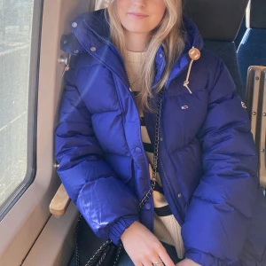 Tommy Hilfiger dunjacka - Säljer min trogna vinterjacka! Är i en jättefin blå nyans och i gott skick. Enda defekten är att det är lite sminkfläckar längst upp vid dragkedjan. Annars är den i super skick. Hör av er vid intresse! Köptes för 1500kr