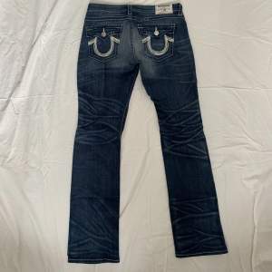 Jeans från True Religion med slitningar framtill, lågmidjade och lätt utsvängda 