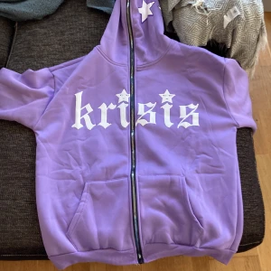 Lila World krisis zip up hoodie - En ljuslila world krisis zip up hoodie i storlek S men jag skulle nog säga storlek M för en bra passform. Den är lite stor. Använd ett fåtal gånger, inget som är sönder eller så. Materialet är tunt men ändå mjukt. 