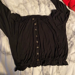 Off shoulder tröja - En svart off shoulder tröja med knappar och en liten volang nedtill. Lappen är tyvärr bortklippt men har för mig att den är från HM och stl M men passar även S