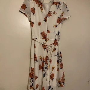 Blommig klänning - Blommig klänning med snörning runt magen, använd en gång. Ihopsydd lite vid bysten 