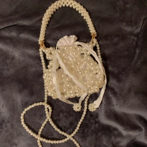 Mini pärlväska🤍🎀 - Super söt mini väska i pärlor. Finns en liten tygpåse i som man kan förvara bland annat sin mobil, nycklar, plånbok för bara (kort), något läppstift osv..❤️👍🏻 perfekt till en utekväll 