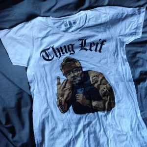 Thug Leif GW tisha - Tisha från svenska märket Rock Paper Scissors med allas käraste Leif GW i gangsterstajl. Använd 1 gång. Trycket är fräscht, i mycket gott skick. Skriv i chatt vid intresse. Möts upp i Hägersten