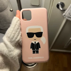 Mobil skal - Ett äkta Karl Lagerfeld skal, till iPhone 11 PRO Max. Som ny,endast 2 små defekter.K på Karl har längst ner ”suddats ut” som man kan se på bilen. Även en repa/hål vad man nu ska kalla det vid på och av knappt, det kan man se på sista bilden. Ny pris 500kr