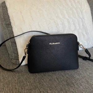 Flora & co väska - Säljer denna svarta Flora & co handväskan för 60kr. Väskan är nästintill oanvänd och är i ett fint skick! Man kan justera längden på axelbanden.