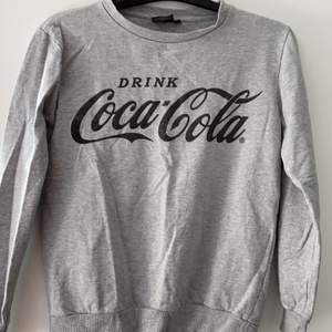 En grå Coca-Cola tröja i använt skick. Köparen står för frakten.