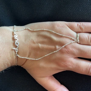 Handsmycke Gina tricot - Så fett o coolt handsmycke. Silverfärgad står LOVE på. Ringen är ställbar. Just nu 17mm. Reglerbar längd runt handled. Buda gärna. Frakt 15kr