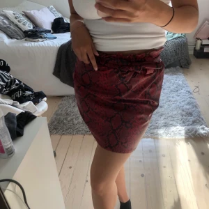 Röd skinnkjol - En supercool röd kjol i fakeläder och med ett svart snakeprint, knytes i midjan och är väldigt bekväm! Köparen står för frakt❤️❤️