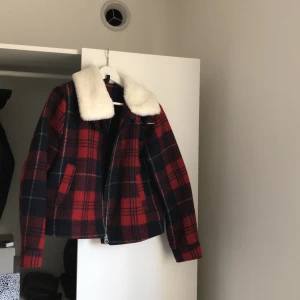 Jacka  - En röd, blå och vit randig jacka från H&M med fina detaljer. Knappt använd och priset kan diskuteras. Möts upp i Sthlm. Fraktar ej!