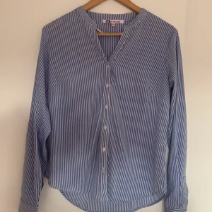 Skjorta - En blårandig skjorta från okänt märke. Snygg att ha uppknäppt för axeln. Använd ca 2 gånger