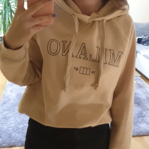 Gina Tricot hoodie - En superskön beige hoodie från Gina Tricot med snören och ett tryck! Jättemjuk på insidan och verkligen asgosig. Två fläckar som knappt syns, en under trycket och en fläck precis på vänstra armen, syns dock inte när man har på sig hoodien. Frakt på 66 kr!