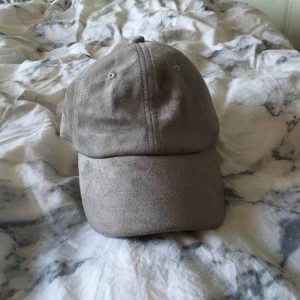 - Grå suede keps från JFR. Justerbar storlek (kvinna).