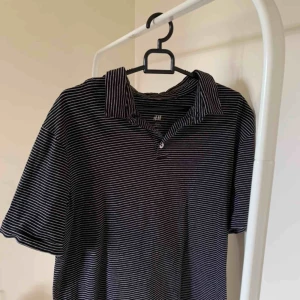  - Mörkblå polo med vita ränder. Knappt använd. Frakt ingår i priset!!