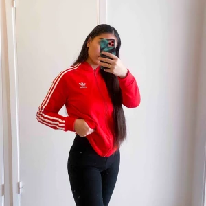  - Jätte fin röd adidas jacka/tröja med vita ränder. Endast använd ett fåtal gånger men den har ett liiiitet hål precis vid dragkedjan därav lite billigare pris. DM för bild ☺️. Nytt pris 499kr. Köp ihop med min svarta adidasjacka och få båda för 300kr🥰💘