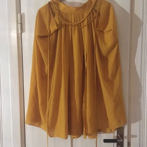  - Fin vid kjol i senapsgul, från H&M. Två fickor, och ett tunt band att knyta i midjan. 100% polyester.  Fint skick. Har swish, köparen står för frakt.