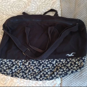  - Hollister väska, som fungerar både som skolväska eller weekendbag mm. I väldigt bra skick, kan skicka fler bilder vid intresse! Mörkblå med blommigt mönster nertill och ett stort innerfack.