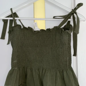 Mörk grönt linne - Knytena på axlarna går att knyta lösare eller tajtare 