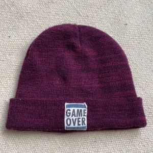 GAME OVER stickad mössa  - mysig mössa med coola detaljer. Använd men fin, Köparen står för frakten!