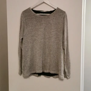 Gråa  tröja  - Grå tröja med silkens innertyg. Och med 3 svarta rosetter på baksidan med en slitz. 