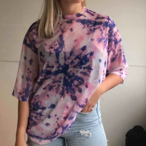  - Rosa/lila tie-dye mesh t-shirt från junkyardcom  Använt ca 2-4 gånger, ny skick Modell av en lång oversized t-shirt i rosa mesh material med lila och lite svarta tie-dye detaljer  Kommer inte ihåg ny pris,