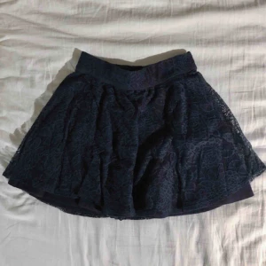 Hollister kjol - Kort spetskjol från Hollister. Mörkblå. OBS, väldigt liten i storlek! Frakt tillkommer om den ska skickas!