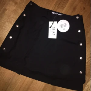  - Popper kjol från NAKD i svart färg med silvriga knappar, aldrig använd; prislapp kvar. Säljes för 100kr i storlek 36 🌸