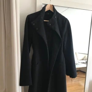  - Klassisk svart kappa, säljer pga för många.  Jag är 163cm och den når mig på längd precis till knäna.  Passar en XS-S. Väldigt sparsamt använd, kappan är egentligen som ny. Mycket varm och skön.