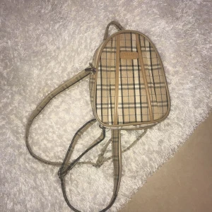  - Liten rutig ryggsäck, man kan även dra ihop banden med dragkedja och ha framme på magen! 