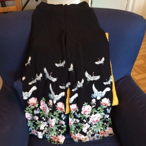  - Snygga vintagebyxor! Säljs för att de är för små. Snyggt tryck med tranor, helsvarta med en slits på vardera sida benen