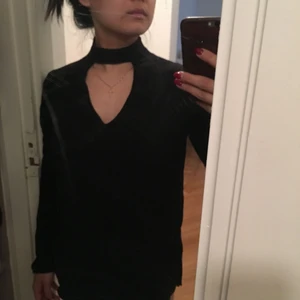  - Fintröja med liten v-öppning vid halsen. Tyget känns lyxigt, knäpps med kedja bakom halsen. Lite vida armar