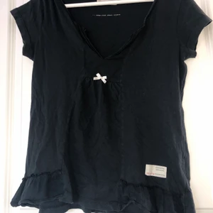 Topp från Odd Molly - ”Homeland short sleeve” från Odd Molly. Storlek 0 (minsta storleken), passar XS-S. Färgen är mörkgrå🖤 Har volanger nertill på sidorna. Nypris ca 500-600 kr, mitt pris 150 kr.  💛🧡❤️