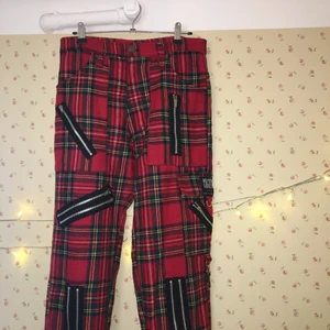 Skotskrutiga byxor med blixtlås - Ascoola klassiska skotskrutiga byxor med en massa blixtlås, anarkiknapp och en extra ficka på knäet. Riktigt bra kvalitet, köpta på Blue fox för 600 kr! Fråga om du vill att jag ska ta mått!