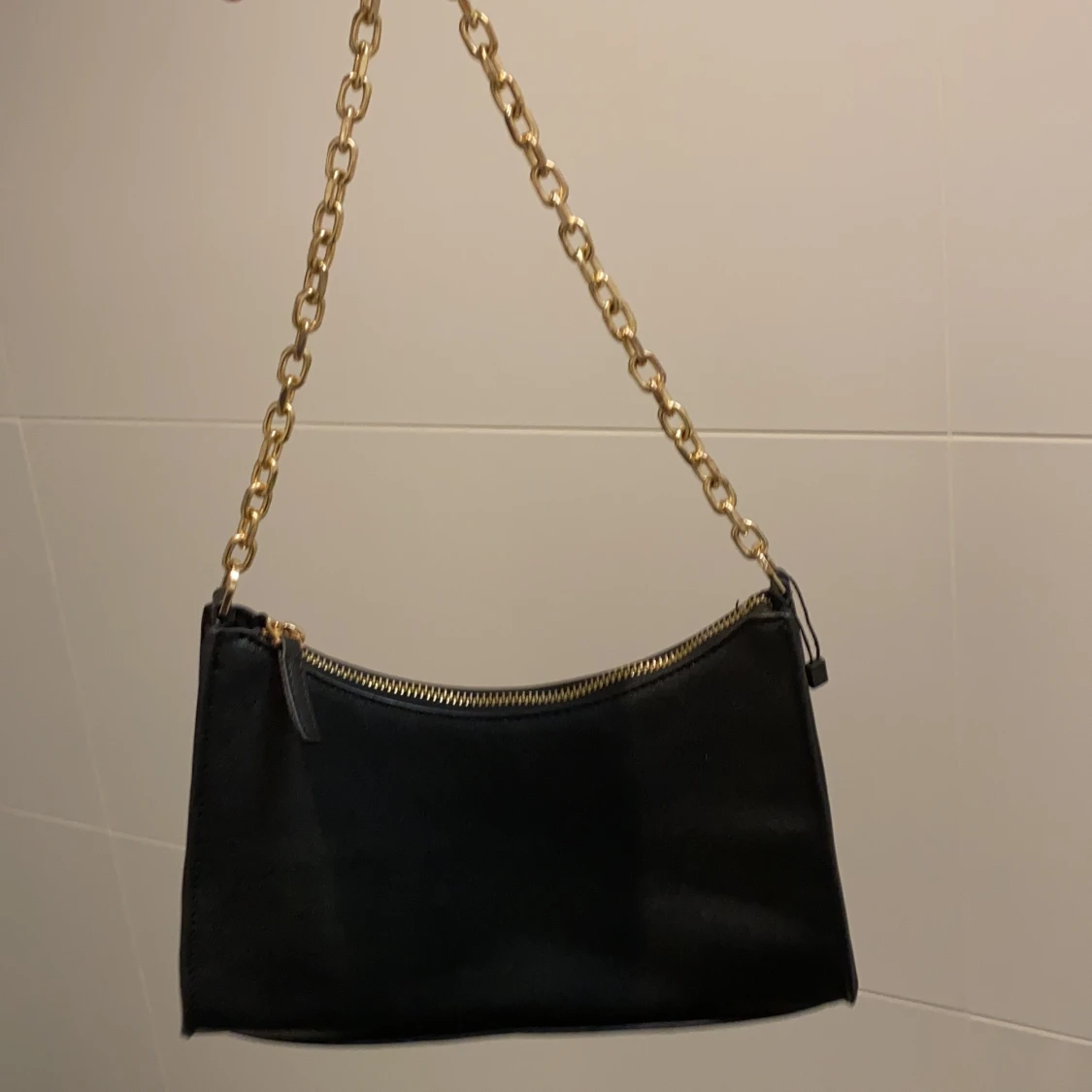 Svart axelväska med guldkedja och guld ditaljer från mango