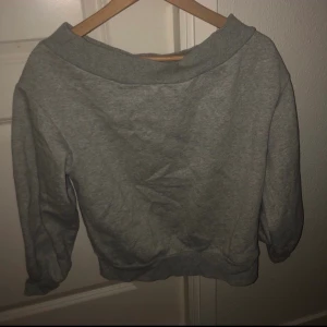 Mjukis tröja  - Grå ”off the shoulder” mjukis tröja. Aldrig använd. Storlek S. Kan passa som en crop top om man vill det. Köparen står för frakten och betalning sker via Swish.