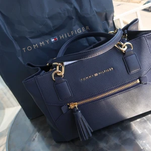 Tommy Hilfiger väska  - Säljer min fina Tommy Hilfiger väska, använd Max 3 ggr. Väskan har även axelrem för att kunna hänga den, super fint skick. Orginal. Påsen följer ej med.