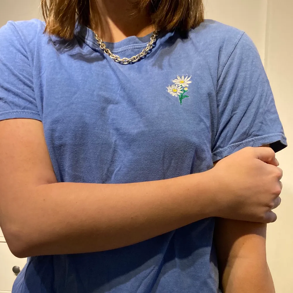 En söt ljusblå t-shirt med en blomma på! Säljer pga att den inte kommer till användning...en liten fläck är på framsidan av tröjan vilket du kan se på sista bilden! Köparen står för frakten . T-shirts.