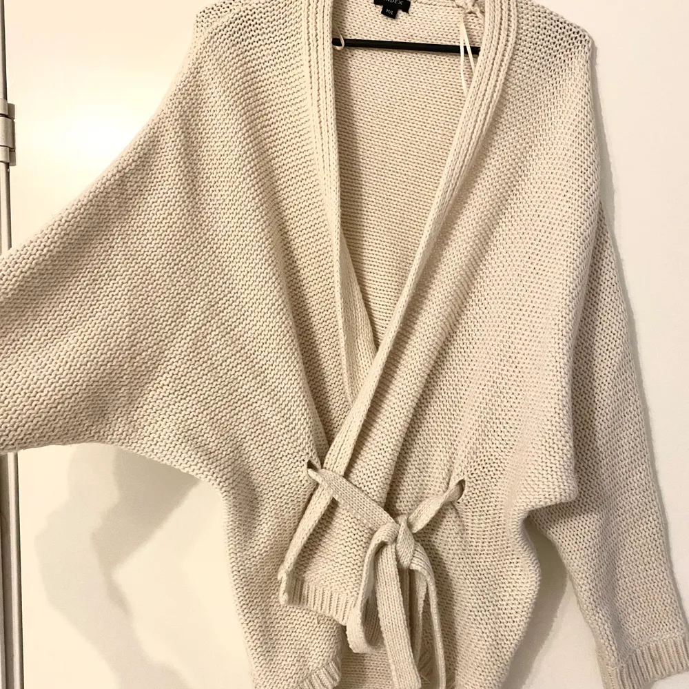 Oanvänd tjock cardigan med knytning på framsida. . Neuleet.