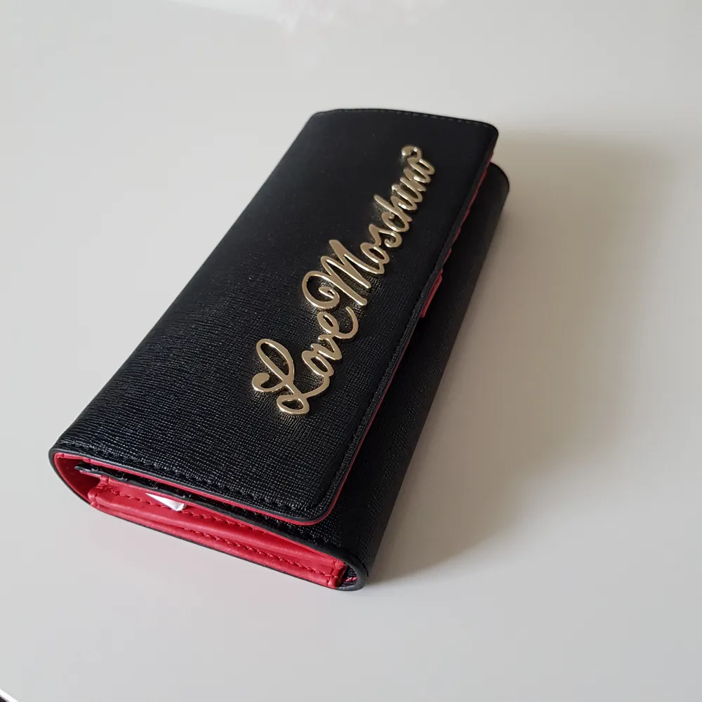 Splitter ny plånbok från märket Moschino (Love Moschino).  Den är självklart äkta (kvitto finns på mail). Svart och röd med guldiga detaljer. . Övrigt.