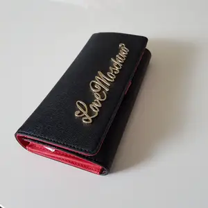 Splitter ny plånbok från märket Moschino (Love Moschino).  Den är självklart äkta (kvitto finns på mail). Svart och röd med guldiga detaljer. 
