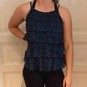  - Fint blått linne med vita prickar. Flera volanger, passar en S