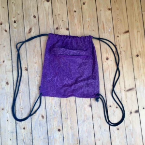  - Gympapåse i lila tyg med fint mönster. Finns två fack, ett på utsidan och ett på insidan som båda stängs med dragkedja.   Knappt använd så i superskick!
